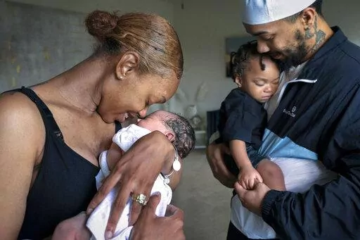 Aaliyah Wright, 25, of Washington, nuzzles her newborn daughter Kali, as her husband Kainan Wright, 24, of Washington, holds their son Khaza, 1, as he falls asleep, during a visit to the children's grandmother in Accokeek, Md., Tuesday, Aug. 9, 2022. A landmark social program is being pioneered in the nation’s capital. Coined “Baby Bonds,” the program is designed to narrow the wealth gap. The program would provide children of the city’s poorest families up to $25,000 when they reach adul