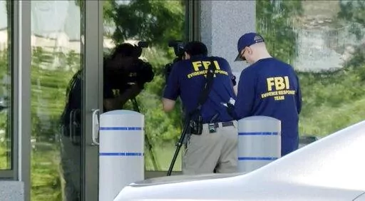 In this still image taken from WKEF/WRGT video, members of the FBI Evidence Response Team work outside the FBI building in Kenwood, Ohio, Thursday, Aug. 11, 2022. An armed man decked out in body armor tried to breach a security screening area at an FBI field office in Ohio on Thursday, then fled and was injured in an exchange of gunfire in a standoff with law enforcement, authorities said. (Courtesy WKEF/WRGT via AP)