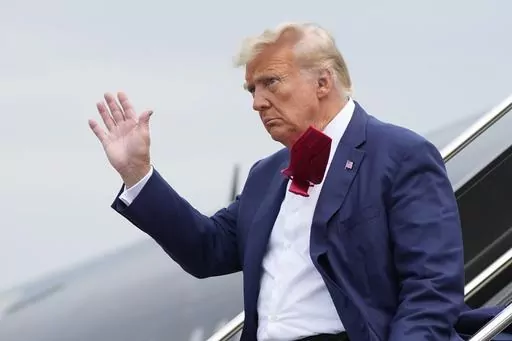 Former President Donald Trump waves as he steps off his plane at Ronald Reagan Washington National Airport, Aug. 3, 2023, in Arlington, Va. A slim majority of Americans approve of the U.S. Justice Department indicting Trump over his efforts to remain in office after losing the 2020 election, according to a new poll from The Associated Press-NORC Center for Public Affairs Research. (AP Photo/Alex Brandon, File)