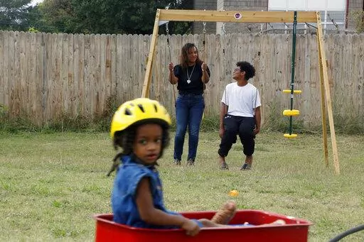 Rosalia Tejeda, talks with her 13-year-old son, Juscianni Blackeller, while her 2-year-old daughter, Audrey Gray, rides in a wagon in their backyard in Arlington, Texas, on Sunday, Oct. 24, 2021. As Tejeda has learned more about health risks posed by fracking for natural gas, she has become a vocal opponent of a plan to add more natural gas wells at a site near her home. On Tuesday, Jan. 4, 2022, the Arlington City Council voted 5-4 to reject the request by Total Energies to drill additional gas