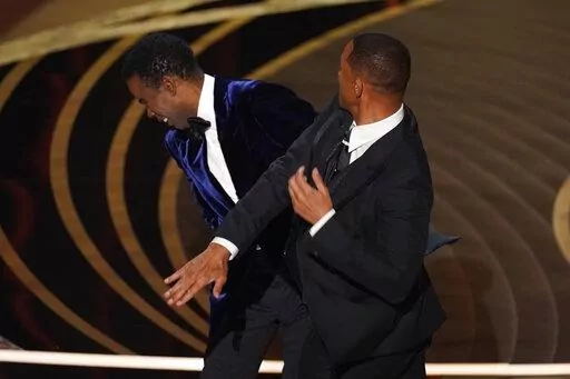 Will Smith, right, hits presenter Chris Rock on stage while presenting the award for best documentary feature at the Oscars on Sunday, March 27, 2022, at the Dolby Theatre in Los Angeles.  On Friday, April 1, The Associated Press reported on stories circulating online incorrectly claiming a photo shows Rock wearing a pad on his cheek during the incident at the Oscars where Smith slapped him. (AP Photo/Chris Pizzello, File)