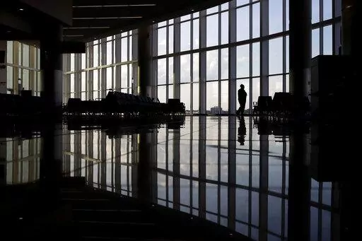 In this June 1, 2020 file photo, a woman looks through a window at a near-empty terminal at an airport in Atlanta. An influential health guidelines group says U.S. doctors should regularly screen adults for anxiety. It’s the first time the U.S. Preventive Services Task Force has recommended anxiety screening in primary care for adults without symptoms. The report released Tuesday, Sept. 20, 2022 is open for public comment until Oct. 17. (AP Photo/Charlie Riedel, File)
