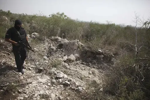 An officer walks past a hole that police say was used as a mass grave, near San Fernando, Tamaulipas state, Mexico, April 27, 2011. The body of 17-year-old Guatemalan Yovanny was found among nearly 200 others in clandestine gravesites, discovered in April and May 2011 near San Fernando. (AP Photo/Alexandre Meneghini, File)