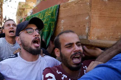 Mourners chant slogans as they carry the coffin of Palestinian Abdul-Al Omar Abdul-Al, 24, who was on a boat carrying migrants from Lebanon that sank in Syrian waters, during his funeral processions, in the Palestinian refugee camp of Nahr el-Bared near the northern city of Tripoli, Lebanon, Saturday, Sept. 24, 2022. Thousands of Palestinians held prayers in northern Lebanon Saturday for one of the scores of migrants who lost their lives this week when their boat sank off Syria's coast. (AP Phot