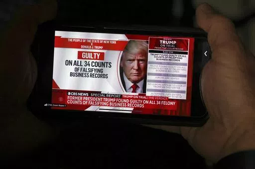 A member of the media looks at news of former President Donald Trump on his phone after the conclusion of Trump's hush money trial, in New York, Thursday, May 30, 2024. (Michael M. Santiago/Pool Photo via AP)