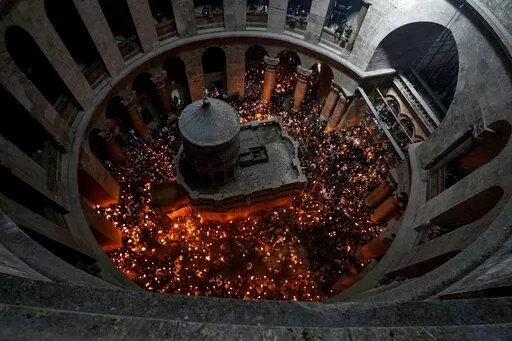 Christian pilgrims hold candles as they gather during the ceremony of the Holy Fire at Church of the Holy Sepulchre, where many Christians believe Jesus was crucified, buried and rose from the dead, in the Old City of Jerusalem dead, Saturday, April 23, 2022. (AP Photo/Tsafrir Abayov)