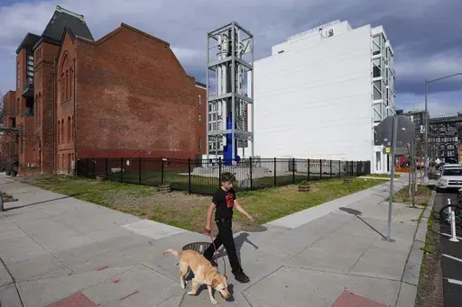 A youth walks a dog past a Last Energy prototype of a microreactor on display at the corner of 10th and V Street NW in Washington, Tuesday, March 25, 2025. (AP Photo/Pablo Martinez Monsivais)