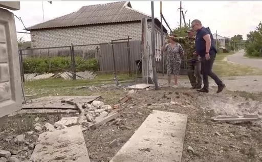 This image taken from a video shows people indicating a damaged building in the Belgorod region, Russia, Monday, May 22, 2023. Russian troops and security forces fought for a second day Tuesday against an alleged cross-border raid that Moscow blamed on Ukrainian military saboteurs but which Kyiv portrayed as an uprising against the Kremlin by Russian partisans. Vyacheslav Gladkov, governor of the Belgorod region on the Ukraine border, said forces continued to sweep the rural area around the town