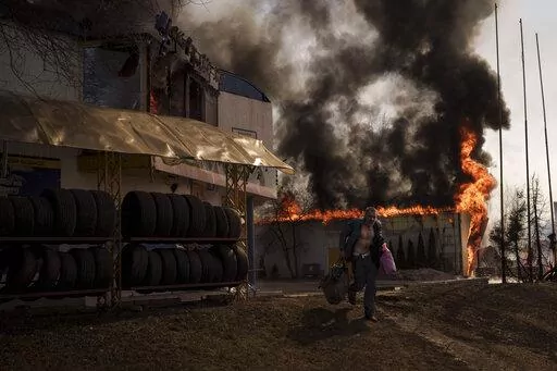 A man recovers items from a shop that caught fire from a Russian attack in Kharkiv, Ukraine, Friday, March 25, 2022. (AP Photo/Felipe Dana)