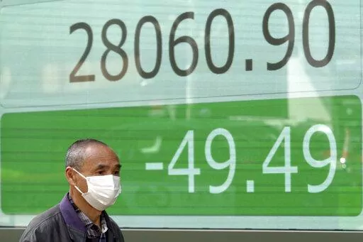 A man wearing a protective mask walks in front of an electronic stock board showing Japan's Nikkei 225 index at a securities firm Friday, March 25, 2022, in Tokyo. Asian stock markets fell Friday after Western governments promised new sanctions on Russia and President Vladimir Putin tried to prop up Moscow's sinking ruble by threatening to require Europe to use it to pay for gas exports. (AP Photo/Eugene Hoshiko)