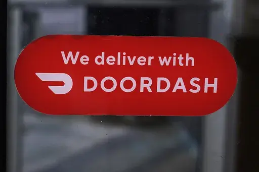 A DoorDash sign is posted on the door of a Dunkin' Donuts franchise, Feb. 27, 2023, in Methuen, Mass. (AP Photo/Charles Krupa, File)