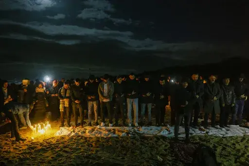 Survivors and relatives of the victims pray, Monday, Feb. 26, 2024, at the site where a migrant boat capsized in the early morning of Sunday, Feb. 26, 2023, at a short distance from the shore in Steccato di Cutro, in the Italian southern tip, killing at least 94 people. Survivors and family members of the victims gathered at the same time on the day of the disaster for a commemoration on the first anniversary. (AP Photo/Valeria Ferraro)
