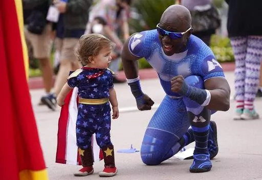 Jay Acey, right, dressed as A-Train from the television series "The Boys," mingles with Maddox Cruz, 1, of Orange, Calif., outside Preview Night at the 2022 Comic-Con International at the San Diego Convention Center, Wednesday, July 20, 2022, in San Diego. (AP Photo/Chris Pizzello)