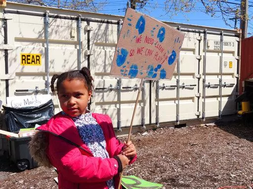 Eight-year-old Sapphire Tate holds a sign before a protest against a proposed backup power plant for a sewage treatment facility in Newark, N.J., on Wednesday, April 20, 2022. The Passaic Valley Sewerage Commission is pushing forward with the gas-fired power plant just months after New Jersey Gov. Phil Murphy ordered them to pause it to ensure that the project does not violate a soon-to-take-effect environmental justice law designed to protect communities that are already overburdened with sourc