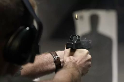 A man fires his pistol at an indoor shooting range during a qualification course to renew his Carry Concealed handgun permit at the Placer Sporting Club, July 1, 2022, in Roseville, Calif. A federal judge on Wednesday, Dec. 20, 2023, temporarily blocked a California law that would have banned carrying firearms in most public places, ruling that it violates the Second Amendment of the U.S. Constitution and deprives people of their ability to defend themselves and their loved ones. (AP Photo/Rich 