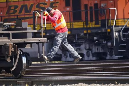 A worker rides a rail car at a BNSF rail crossing in Saginaw, Texas, Wednesday, Sept. 14, 2022. Business and government officials are preparing for a potential nationwide rail strike at the end of this week while talks carry on between the largest U.S. freight railroads and their unions. (AP Photo/LM Otero)