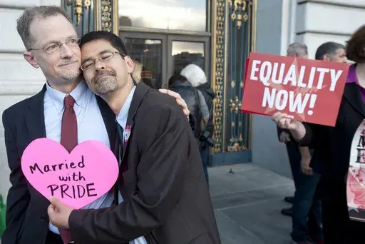 John Lewis, left, and Stuart Gaffney embrace outside San Francisco's City Hall shortly before the U.S. Supreme Court ruling cleared the way for same-sex marriage in California, June 26, 2013. The U.S. Census Bureau on Tuesday, June 11, 2024, reported that same-sex spouses were typically younger, had more education and were more likely to be employed than those in opposite-sex marriages. (AP Photo/Noah Berger, File)