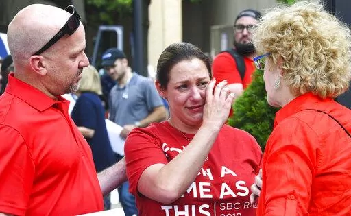 In this Tuesday, June 11, 2019 file photo, Jules Woodson, center, of Colorado Springs, Colo., is comforted by her boyfriend Ben Smith, left, and Christa Brown during a demonstration outside the Southern Baptist Convention's annual meeting in Birmingham, Ala. First-time attendee Woodson spoke through tears as she described being abused sexually by a Southern Baptist minister. A blistering report on the Southern Baptist Convention’s mishandling of sex abuse allegations, released on Sunday, May 2
