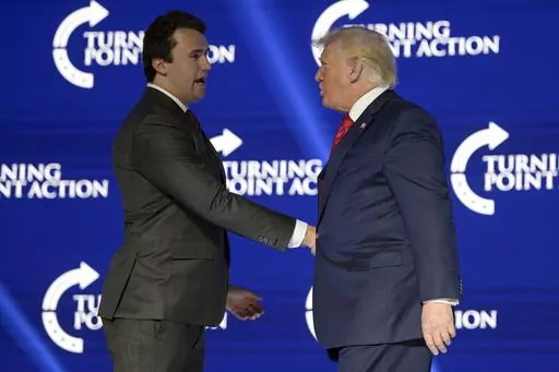 Former President Donald Trump, right, shakes hands with Turning Point CEO Charlie Kirk before speaking during the Turning Point USA Student Action Summit, July 23, 2022, in Tampa, Fla. The nonprofit rocketed to prominence by latching on to Trump’s 2016 campaign and has raised roughly a quarter-billion dollars since, much of it spent cultivating conservative influencers and hosting glitzy events. The organization also enriched Kirk and his allies, according to an Associated Press review of publ