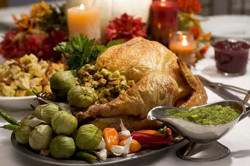 A grill-roasted brined turkey is presented on a table in Concord, N.H. Turkey is the center of most Thanksgiving meals, but it’s important to handle raw poultry properly to avoid spreading bacteria that can send your guests home with an unwanted side of food poisoning.  (AP Photo/Larry Crowe, File)