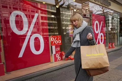 A woman walks with purchases past a store in Berlin, Germany, Friday, April 1, 2022. Europe ended a bad year for inflation with some relief as price gains eased again, though they still rose a painful 9.2% in December, according to data released Friday, Jan. 6, 2023. (AP Photo/Pavel Golovkin, File)