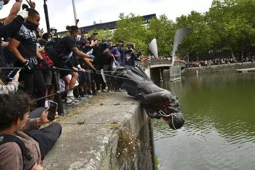 Protesters throw a statue of Edward Colston into the Bristol harbour during a Black Lives Matter protest rally, Bristol, England, June 7, 2020. Four anti-racism demonstrators were cleared Wednesday Jan. 5, 2022, of criminal damage in the toppling of a statue of a 17th century slave trader during a Black Lives Matter protest in southwestern England 18 months ago. (Ben Birchall/PA via AP, File)