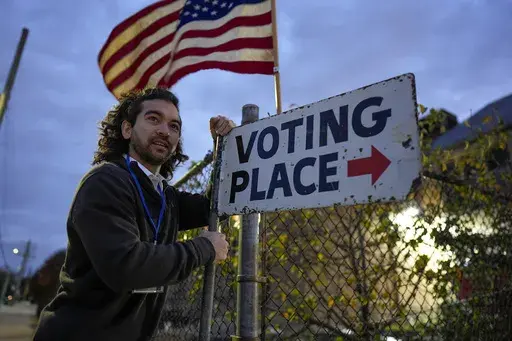 Election day worker Sean Vander Waal prepares to open a polling place,Tuesday, Nov. 5, 2024, in Dearborn, Mich. (AP Photo/Charlie Neibergall)