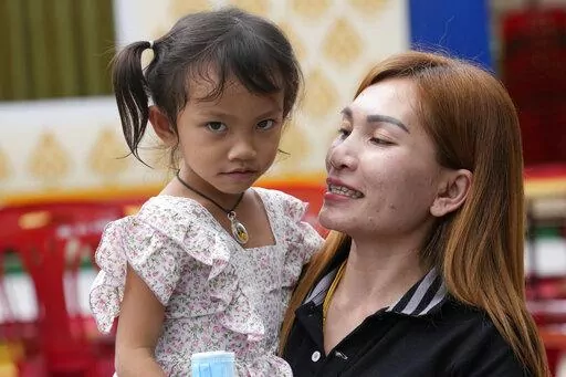 Paweenuch Supolwong, 3, the only child to emerge unscathed from the mass killing attack at the day care center, is held by her mother Anonpai Srithong, 35, during an interview inside Wat Si Uthai temple temple in Uthai Sawan, north eastern Thailand, Saturday, Oct. 8, 2022. A former police officer burst into a day care center in northeastern Thailand on Thursday, killing dozens of preschoolers and teachers before shooting more people as he fled. (AP Photo/Sakchai Lalit)
