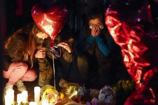 Women pause at a memorial at a vigil honoring the victims of a shooting at the Star Ballroom Dance Studio on Monday, Jan. 23, 2023, in Monterey Park, Calif. A gunman killed multiple people late Saturday amid Lunar New Years celebrations in the predominantly Asian American community. (AP Photo/Ashley Landis)
