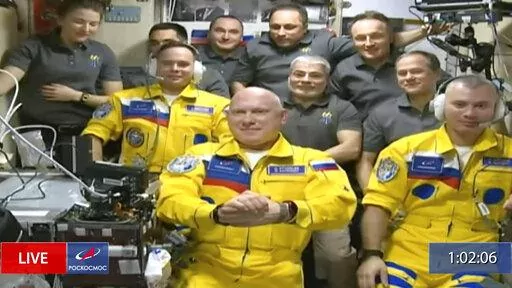 In this frame grab from video provided by Roscosmos, Russian cosmonauts Sergey Korsakov, Oleg Artemyev and Denis Matveyev are seen during a welcome ceremony after arriving at the International Space Station, Friday, March 18, 2022, the first new faces in space since the start of Russia’s war in Ukraine. The crew emerged from the Soyuz capsule wearing yellow flight suits with blue stripes, the colors of the Ukrainian flag. (Roscosmos via AP)