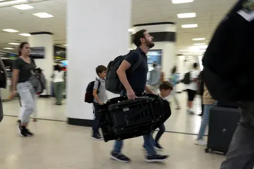 Travelers walk through the concourse at Miami International Airport on May 23, 2024, in Miami. (AP Photo/Lynne Sladky, File)