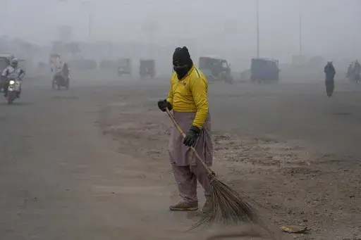 A sweeper cleans as smog envelops the area and reduces visibility in Lahore, Pakistan, Jan. 11, 2024. (AP Photo/K.M. Chaudary, File)