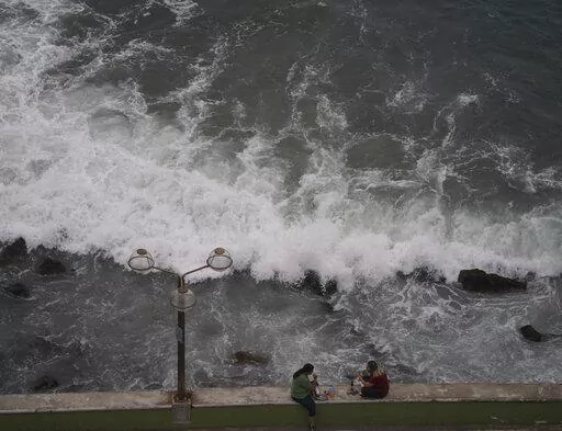 People relax at the beach front in Mazatlan, Mexico, Sunday, Oct. 2, 2022. Hurricane Orlene, at Category 3 strength, is heading for a collision with Mexico's northwest Pacific coast between the tourist towns of Mazatlan and San Blas. (AP Photo/Fernando Llano)