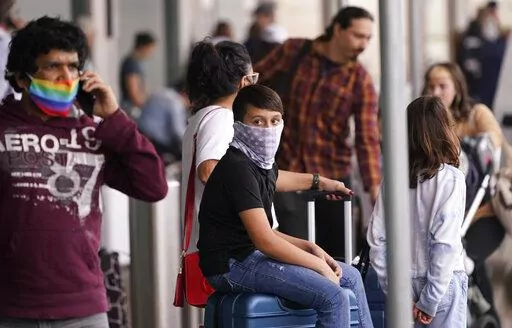 To prevent the spread of COVID-19, air travelers wear masks at Love Field in Dallas, Friday, Dec. 31, 2021. Flight cancellations surged again on the last day of 2021, with airlines blaming it on crew shortages related to the spike in COVID-19 infections.  The new year is bringing more of the same old misery that air travelers in the United States have been enduring for more than a week. Airlines are blaming wintry weather and high numbers of sickouts due to the rising number of COVID-19 infectio