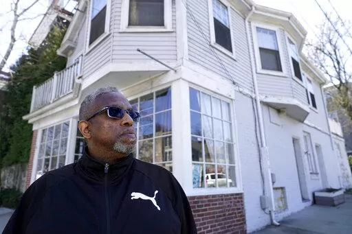 Terrell Osborne, of Providence, R.I., stands for a portrait, Monday, April 11, 2022, in front of an antique shop, that was a general store in the early 1960s, in what was then known as the Lippitt Hill neighborhood, in Providence. As a child growing up in Providence in the late 1950s and 1960s, he watched as huge swaths of his 30-acre neighborhood of Lippitt Hill, a center of Black life at the foot of the stately homes of the city's elite East Side, were taken by eminent domain for redevelopment