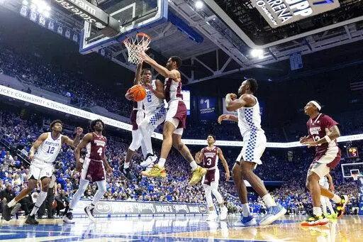 Kentucky guard Sahvir Wheeler (2) passes the ball off while being guarded by Mississippi State guard Iverson Molinar, behind Wheeler, and forward Garrison Brooks, right, during the first half of an NCAA college basketball game in Lexington, Ky., Tuesday, Jan. 25, 2022. (AP Photo/Michael Clubb)