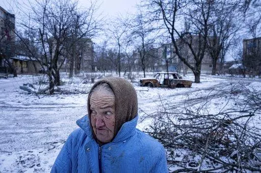Nina Klinkova reacts to a sound of an explosion as she looks for humanitarian aid in Siversk, Donetsk region, Ukraine, Thursday, Jan. 12, 2023. (AP Photo/Evgeniy Maloletka)