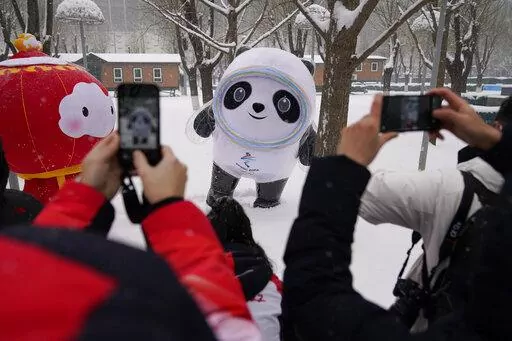 People take photos of Olympic mascot Bing Dwen Dwen, center, and Paralymic mascot Shuey Rhon Rhon, left, in the snow at the 2022 Winter Olympics, Feb. 13, 2022, in Beijing. (AP Photo/Ashley Landis, File)