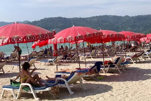 Tourists lounge under umbrellas along Patong Beach in Phuket, Thailand, Friday, March 11, 2022. Thousands of Russian tourists are stranded in Thailand's beach resorts because of the war in Ukraine, many unable to pay their bills or return home because of sanctions and canceled flights.  The crisis in Europe also put a crimp in recovery plans for the Southeast Asian nation’s tourism industry, which has hosted more visitors from Russia than any of its neighbors before the pandemic hit. (AP Photo