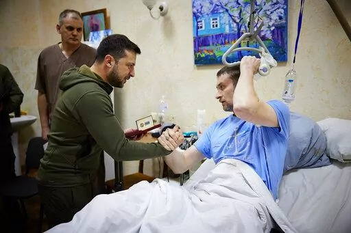 In this photo provided by the Ukrainian Presidential Press Office on Sunday, March 13, 2022, President Volodymyr Zelenskyy, center, shakes hands with a wounded soldier during his visit to a hospital in Kyiv, Ukraine. (Ukrainian Presidential Press Office via AP)