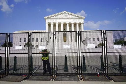 An officer rests on a fence outside the Supreme Court in Washington, Friday, June 24, 2022. The Supreme Court has ended constitutional protections for abortion that had been in place nearly 50 years, a decision by its conservative majority to overturn the court's landmark abortion cases. (AP Photo/Jacquelyn Martin)