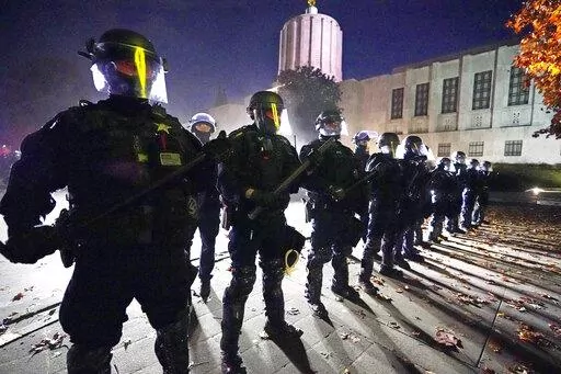 Police line-up at the Oregon State Capitol building where demonstrators gathered during the day Saturday, Nov 7, 2020, in Salem, Ore. A federal civil rights trial against three former Minneapolis police officers seeks to hold them responsible for not stopping George Floyd's murder under Derek Chauvin's knee — and perhaps strike a blow against longstanding police culture that breeds reluctance to rein in fellow officers. (AP Photo/Marcio Jose Sanchez, File)