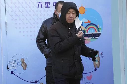 A resident pulls away a mask during COVID test in Beijing, Wednesday, Dec. 7, 2022. In a sharp reversal, China has announced a series of measures rolling back some of the most draconian anti-COVID-19 restrictions. (AP Photo/Ng Han Guan)