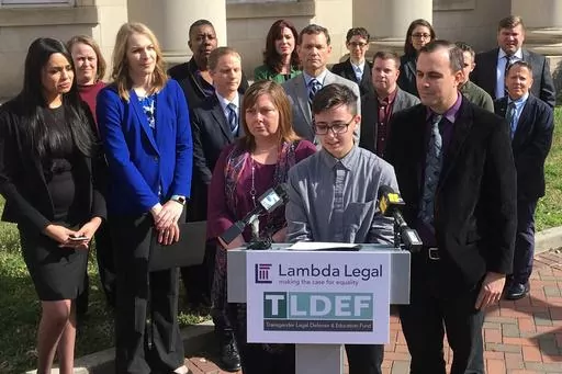 Connor Thonen-Fleck addresses reporters while his parents stand by his side, Monday March 11, 2019, in Durham, N.C., at the announcement of a lawsuit against North Carolina officials over how the state health plan is run. A federal appeals court is considering cases out of North Carolina and West Virginia that could have broad-ranging implications on whether individual states are constitutionally required to cover healthcare for transgender people with government-sponsored insurance. (AP Photo/ 