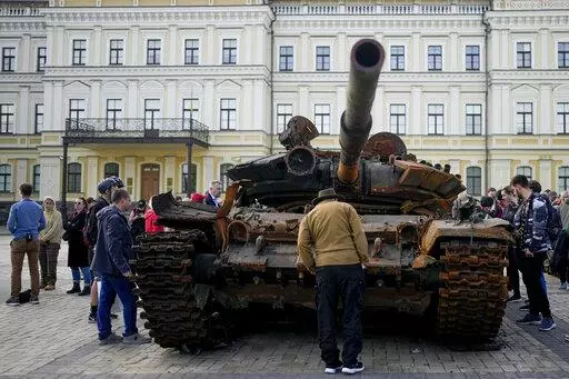 A man looks at a destroyed Russian tank placed as a symbol of war in downtown Kyiv, Ukraine, May 23, 2022. A new report from NewsGuard, a tech firm that tracks disinformation has identified 250 websites actively working to spread Kremlin disinformation.(AP Photo/Natacha Pisarenko, File)