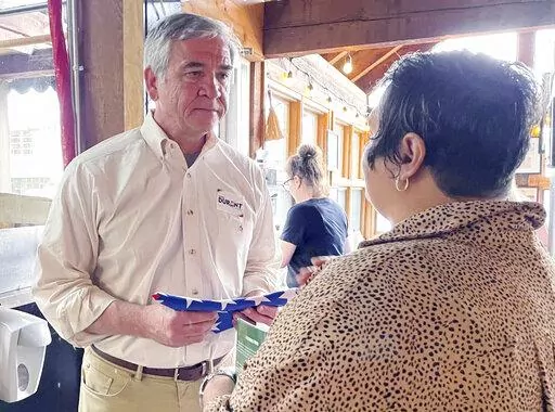 U.S. Senate candidate Mike Durant receives a folded U.S. flag from a supporter during a campaign stop in Homewood, Ala., on Monday, May 23, 2022. Best known as the U.S. helicopter pilot whose capture in Somalia was chronicled in the "Black Hawk Down" book and subsequent movie, Durant is among six people seeking the GOP nomination for the Senate seat being vacated by Sen. Richard Shelby, who is retiring. (AP Photo/Kim Chandler)