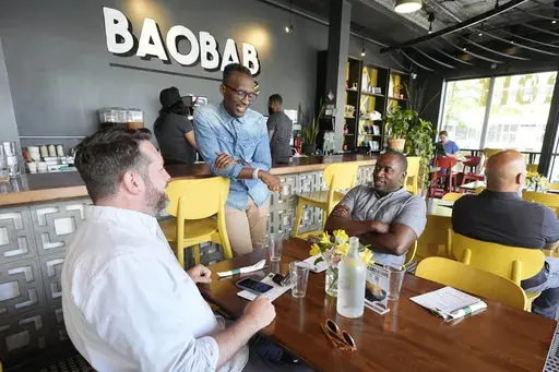 Hamissi Mamba talks to customers at his restaurant, Baobab Fare, Friday, May 24, 2024, in Detroit. For Hamissi Mamba and Nadia Nijimbere _ who own Baobab Fare in Detroit _ a win among the five finalists in the James Beard's "Outstanding Restaurateur" category would be personal. The couple, who fled Burundi about a decade ago, faced a difficult road as refugees opening a business in America. (AP Photo/Carlos Osorio)