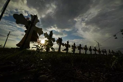 Vehicles pass crosses placed to honor the victims of the shootings at Robb Elementary School, Thursday, Aug. 25, 2022, in Uvalde, Texas. The Texas Department of Public Safety has fired an officer who was at the scene of the school massacre and becomes the first member of the state police force to lose their job in the fallout over the hesitant response to the May attack. (AP Photo/Eric Gay, File)