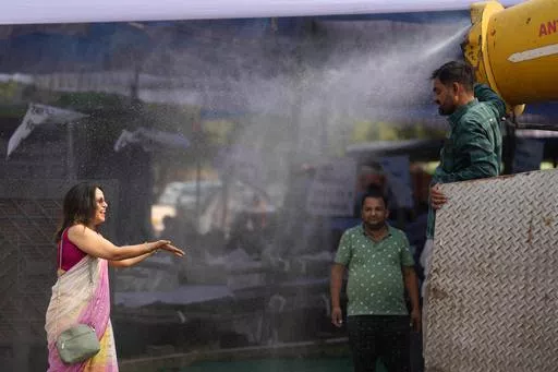 A polling official enjoys a cooling spray of water under intense heat at a distribution venue for Electronic Voting Machines (EVMs) and other election material on the eve of the fifth phase of polling in the six-week-long national election in Lucknow, India, Sunday, May 19, 2024. A top United Nations official says even though climate change makes disasters such as cyclones, floods and droughts more intense, more frequent and striking more places, fewer people are dying from those catastrophes gl