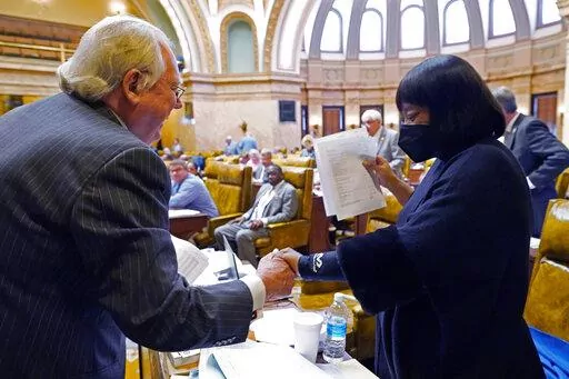House Appropriations Committee Chairman John Read, R-Gautier, left, assures Rep. Omeria Scott, D-Laurel, that she would be receiving an updated grid of the total state support for agencies for fiscal year 2023, in the House chamber at the Mississippi Capitol in Jackson, Miss., Monday, April 4, 2022. (AP Photo/Rogelio V. Solis)